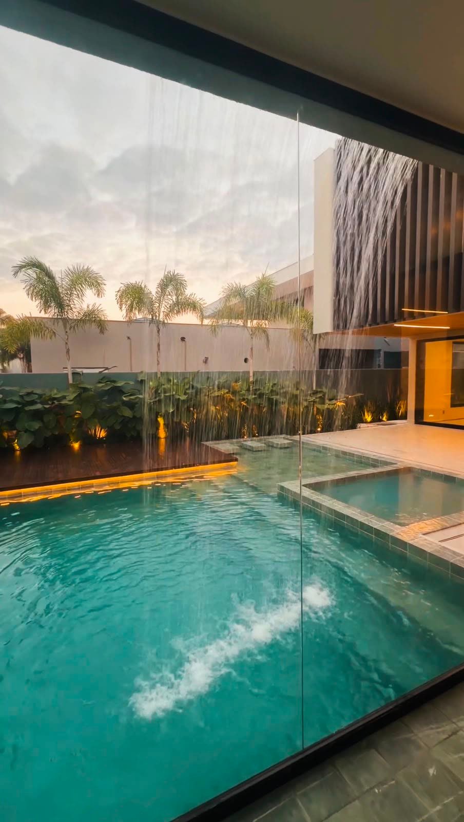 Piscina vista através do vidro, com queda d'água